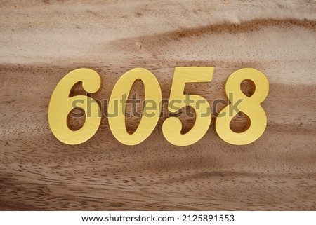 Wooden numerals 6058 painted in gold on a dark brown and white patterned plank background.