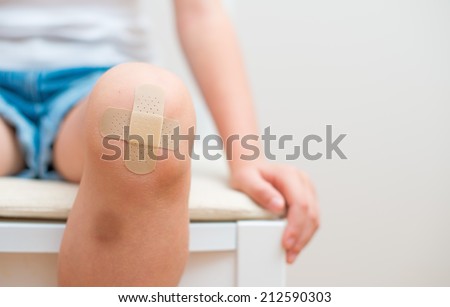 Child knee with an adhesive bandage and bruise. Royalty-Free Stock Photo #212590303