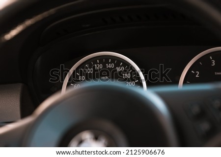 Modern car interior with speedometer and steering wheel in the background. Minimalistic black dashboard, perfect for advertisements and backgrounds. 