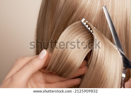 Hairdresser cuts long blonde hair with scissors. Hair salon, hairstylist. Care and beauty hair products. Dyed hair Royalty-Free Stock Photo #2125909832