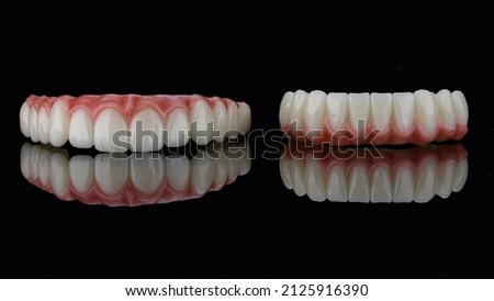 excellent angle on dental prostheses with the gums of the upper and lower jaws on black glass Royalty-Free Stock Photo #2125916390