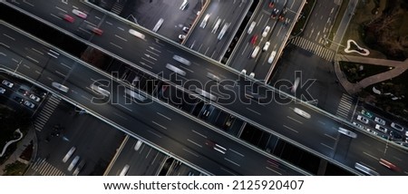 Aerial top down of multilevel elevated road huge traffic junction in modern metropolis city. Night long exposure motion blur of vehicles. Modern development of infrastructure and motorways in China.