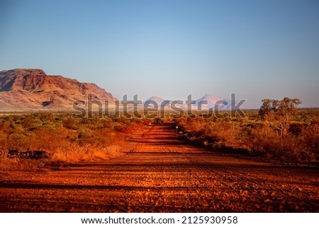 One of the most beautiful red dirt-roads in the Karijini National Park in Western Australia at sunset. Royalty-Free Stock Photo #2125930958