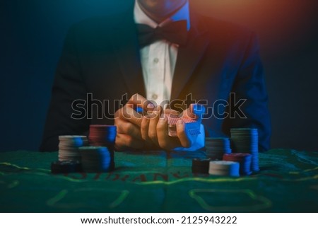Man dealer or croupier shuffles poker cards in a casino on the background of a table,asain man holding two playing cards. Casino, poker, poker game concept Royalty-Free Stock Photo #2125943222