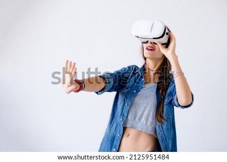 Excited girl getting experience using VR glasses on white background much gesticulating hands. Smiling woman push air while using VR device isolated on white. Future technology concept.