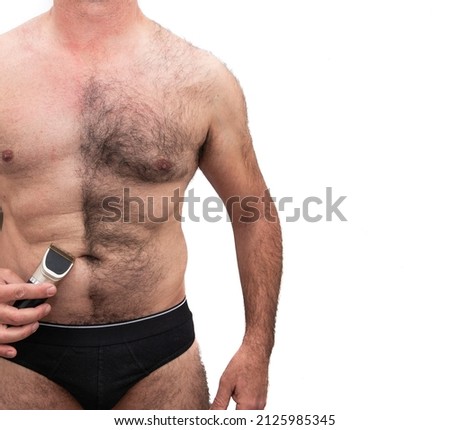 An athletic older Caucasian man, bare chested hairy, holding a razor in his hand, half shaved chest. Isolated on white background.