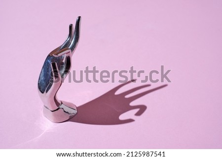 iron Hand Ring Holder, Hand Shaped with shadow on a trendy pink background 