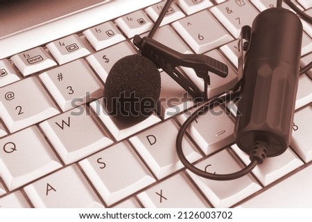 Lavalier microphone on laptop keyboard close up.