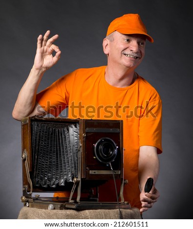 Happy man with vintage wooden photo camera on a dark background