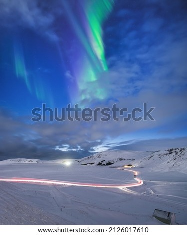 Aurora Borealis in Iceland. Northern Lights over the road. A winter night landscape with bright lights in the sky. Landscape in the north in winter time. A popular place to travel.