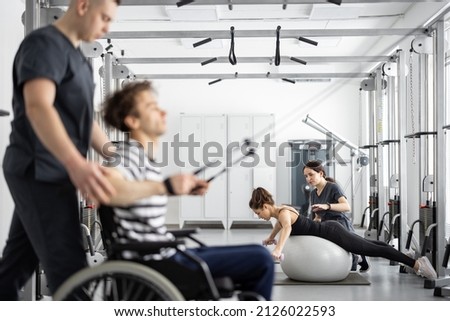 Rehabilitation specialist helps a guy in a wheelchair to do exercise on decompression simulator for recovery from injury Royalty-Free Stock Photo #2126022593