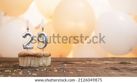 Happy birthday card with candle number 29 in a cupcake against the background of balloons. Copy space happy birthday for twenty nine years old