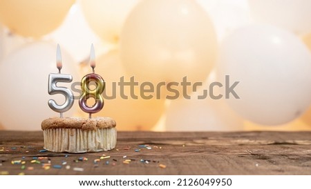 Happy birthday card with candle number 58 in a cupcake against the background of balloons. Copy space happy birthday for fifty eight years old