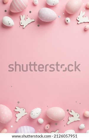 Top view vertical photo of easter decorations shiny confetti easter bunnies lilac pink and white easter eggs on isolated pastel pink background with empty space