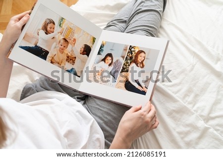 top view. a woman holds a photobook while sitting in bed. family photo shoot. professional printing of photos and albums in the printing, photo laboratory. photographer and designer services. memory. Royalty-Free Stock Photo #2126085191