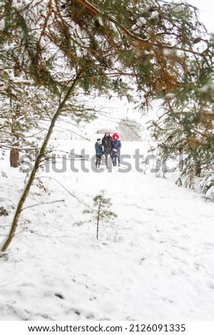 Defocus man in warm hat and child girl and boy on rural winter snowy background holding umbrella. Happy family, cold weather. Time together. Snowy winter, lost in forest. Outside. Out of focus.