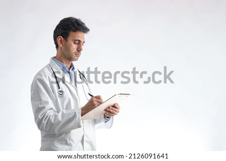 Arab doctor with white coat in profile writing on a folder on white background