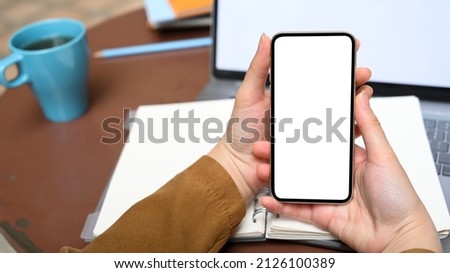Close-up image, Female holding mobile phone white screen mockup over her desk. internet connection, mobile application.