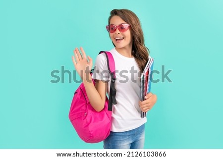 happy teen girl with backpack and copybook ready to study at school waving hello, school