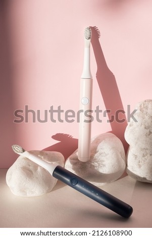 New modern ultrasonic toothbrushes. Dental care supplies with white stones on pink pastel background. Oral hygiene, dental health, healthy teeth. Dental products Ultrasonic vibration toothbrush.