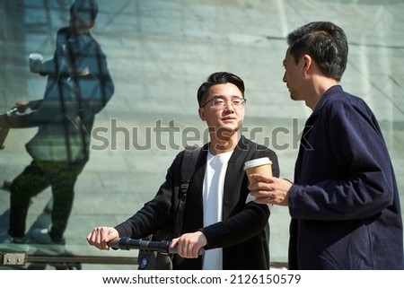 two young asian friends colleagues chatting while walking on street Royalty-Free Stock Photo #2126150579