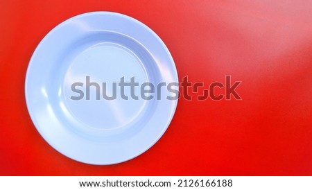 Empty blue plate on red background with space for your meal. Food and beverage concept. Food Photography. High angle view. Flat lay. Space for text. Copy space. Negative space.