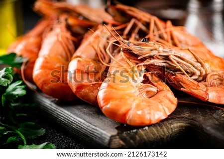 Boiled shrimp on a cutting board with parsley and spices. On a black background. High quality photo