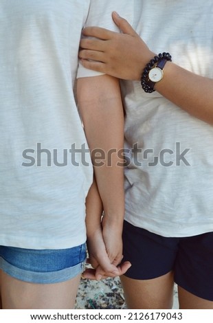 Crop photo of couple wearing matching shirts and short holding hands on the beach