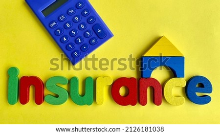 Top view of word Insurance, calculator and wooden model house with yellow paper background.