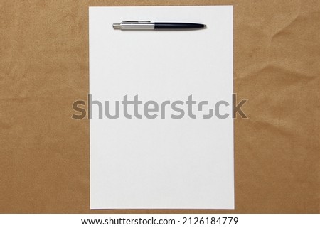 Template of white paper with pen lies on light brown cloth background. Concept of business plan and strategy. Stock photo with empty space for text and design.