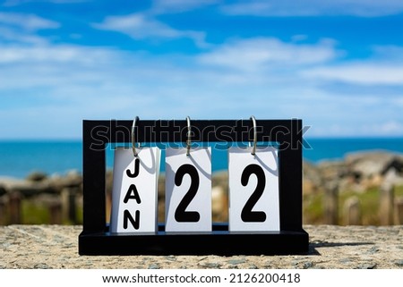Jan 22 calendar date text on wooden frame with blurred background of ocean. Calendar concept