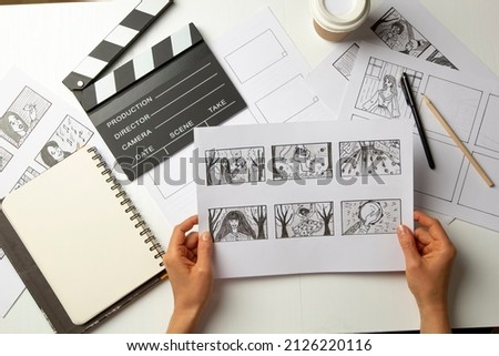 Storyboard in the hands of the artist. Drawn characters for a movie or cartoon on the desktop.