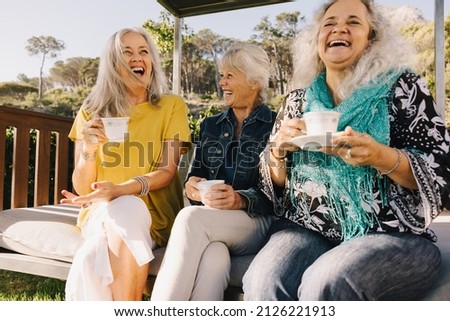 Senior friends laughing happily while having tea Royalty-Free Stock Photo #2126221913