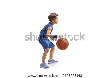 Full length profile shot of a boy in a blue jersey playing basketball isolated on white background Royalty-Free Stock Photo #2126225648