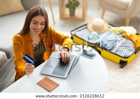 Happy young woman with credit card booking vacation at travel agency or making hotel reservation online, using laptop computer, planning abroad trip at home, copy space Royalty-Free Stock Photo #2126228612