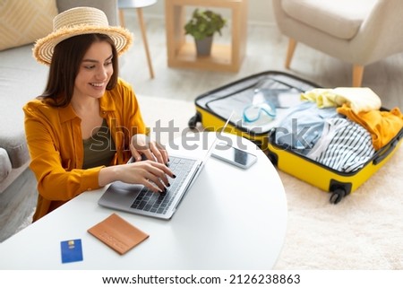 Happy young woman planning vacation travel with laptop pc, reading tourist blog online, booking tickets or hotel room on web, getting ready for abroad journey at home, free space Royalty-Free Stock Photo #2126238863