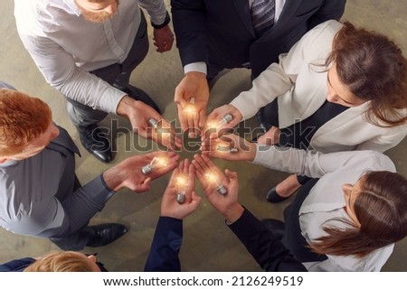 Teamwork and brainstorming concept with businessmen that share an idea with a lamp Royalty-Free Stock Photo #2126249519