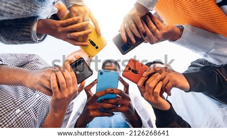 Teens in circle holding smart mobile phones - Multicultural young people using cellphones outside - Teenagers addicted to new technology concept Royalty-Free Stock Photo #2126268641