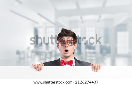 Young businessman holds a banner in front of him with two hands. Place for text