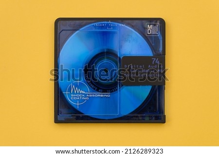 Recordable blue mini disc from the 1990's isolated on yellow background. Close up view from above.