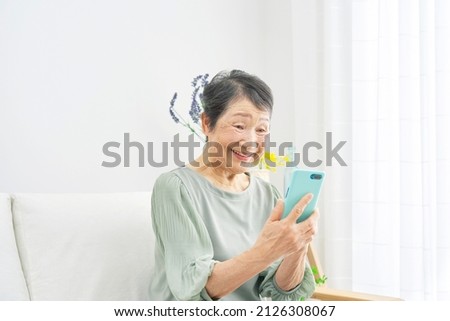 Asian senior woman using the smartphone at home