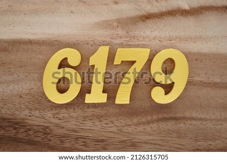Wooden numerals 6179 painted in gold on a dark brown and white patterned plank background.