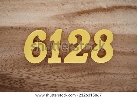 Wooden numerals 6128 painted in gold on a dark brown and white patterned plank background.