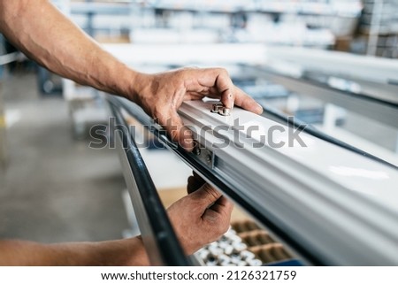 Manual worker assembling PVC doors and windows. Manufacturing jobs. Selective focus. Factory for aluminum and PVC windows and doors production. Royalty-Free Stock Photo #2126321759