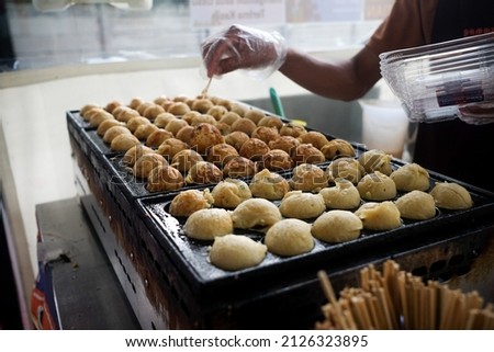 Process to Cooking Takoyaki on hot pan Famous food Osaka Japan street food. Man doing octopus takoyaki Is a snack of Japanese people When chewing the squid, it feels crunchy.