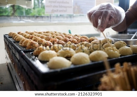Process to Cooking Takoyaki on hot pan Famous food Osaka Japan street food. Man doing octopus takoyaki Is a snack of Japanese people When chewing the squid, it feels crunchy.