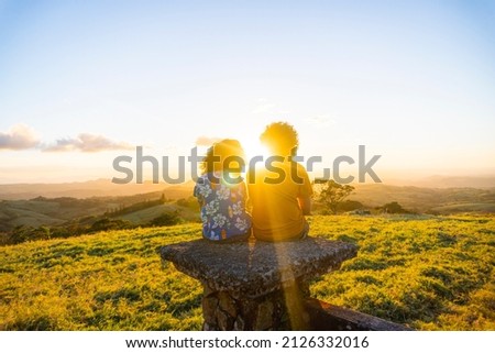Two children sitting together watching the sunset 