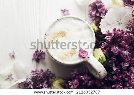Delicious coffee, blooming lilac branch and rose on rustic white wooden background. Hello spring. Flat lay with space for text. Happy mothers day. Good morning still life