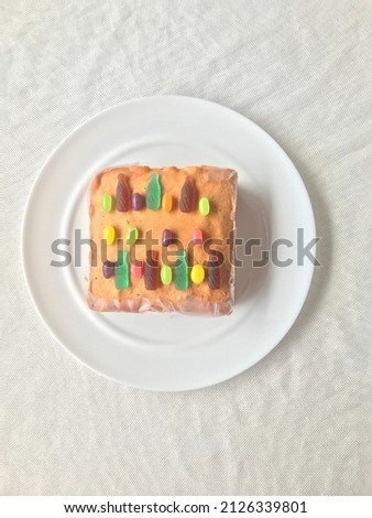 butter cake with colorful jelly candies on a plate at table