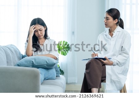 Asian psychology doctor examine and listen to woman patient at home. Attractive beautiful female physician give advise and consult to help young girl solve problem for Psychologic health care in house Royalty-Free Stock Photo #2126369621